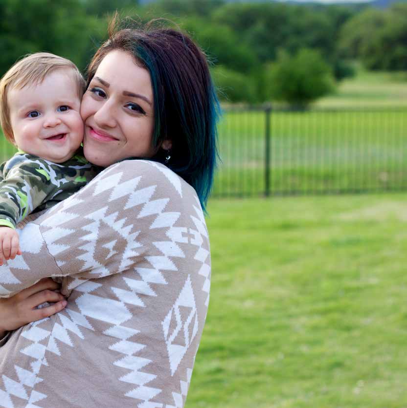 A young mom holding her smiling baby outside