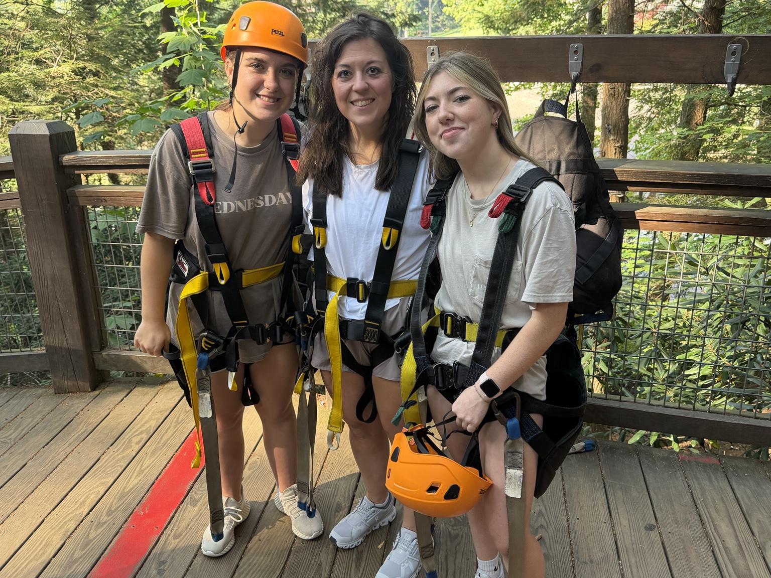 Three people in climbing gear at camp